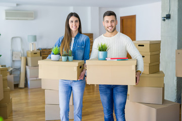 Fototapeta na wymiar Young couple moving to a new home, smiling happy holding cardboard boxes at new apartment