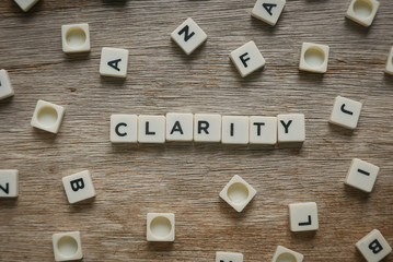 Word Clarity alphabet on wooden background.