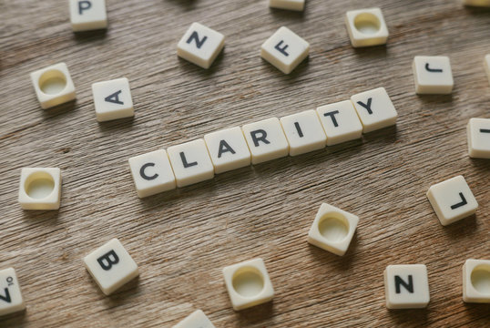 Word Clarity alphabet on wooden background.
