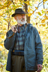 Obraz premium Distempered hunter man with grey beard look away with sadness. Forest background