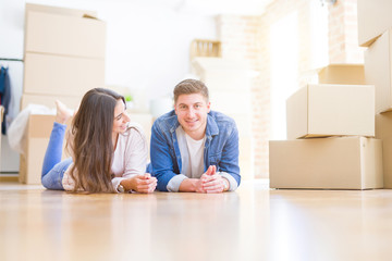 Fototapeta na wymiar Young beautiful couple relaxing lying on the floor around cardboard boxes at home, smiling happy moving to a new house