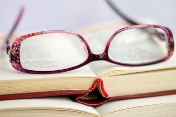 Against the background of opened books with verses are women's glasses for sight