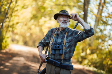 Bearded man stand resting after hunting, look for new trophy. Sunny autumn background
