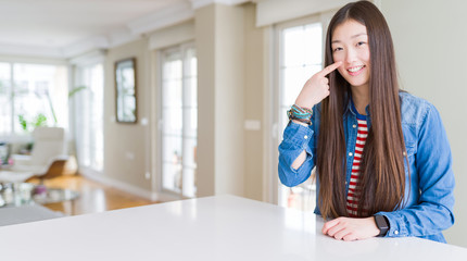 Young beautiful asian woman with long hair wearing denim jacket Pointing with hand finger to face and nose, smiling cheerful. Beauty concept