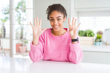 Beautiful african american woman with afro hair wearing casual pink sweater showing and pointing up...