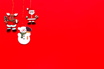 Fototapeta premium Wooden christmas decorations Santa, snowman and deer on red background. Merry Christmas and Happy New Year concept. Top view, flat lay, copy space.