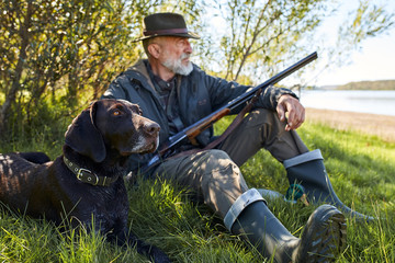 Looking for trophy with dog. Senior man ready to hunt. Sit having rest before hunting