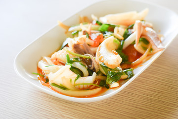 Stir fried squid with salted egg yolk on white dish on table background. thai food.