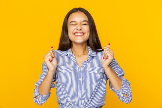 Woman with crossed fingers smiling and atsnding in a hope isolated