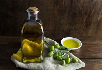 Olive oil and olive berries are on the wooden table.