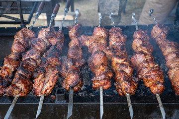 Grilled kebab cooking on metal skewer closeup. Roasted meat cooked at barbecue. BBQ fresh beef meat...