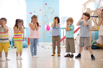 Fototapeta premium Preschool children stand with closed eyes during game in day care