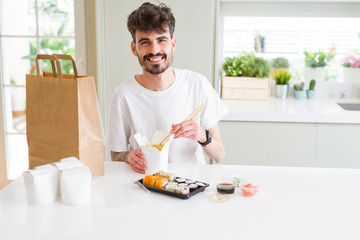 Young man eating sushi asian food and noodles using choopsticks from take away delivery