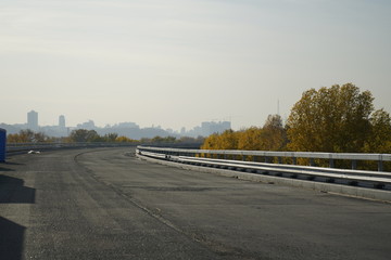 Fototapeta premium Unfinished bridge against the background of the silhouette of the city. Unfinished highway away city. Fender on the autobahn