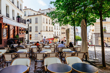 Cozy street with tables of cafe in quarter Montmartre in Paris, France - obrazy, fototapety, plakaty