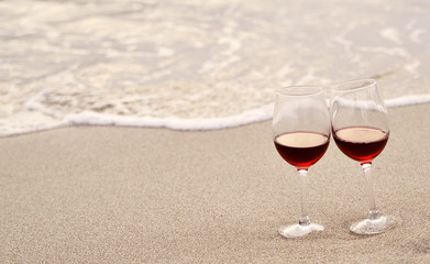 Two wine glasses on sand.