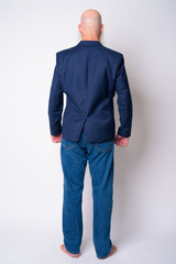 Full body shot rear view of mature bearded bald businessman in suit