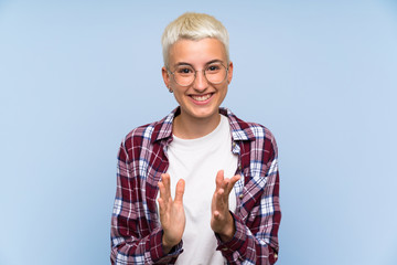 Teenager girl with white short hair over blue wall applauding