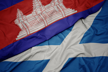 waving colorful flag of scotland and national flag of cambodia.