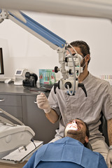 Dental doctor with microscope and hygienic gloves checking the dental health of his patient in a modern clinic