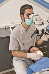 Fototapeta premium Dental doctor with microscope and hygienic gloves checking the dental health of his patient in a modern clinic