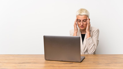 Teenager girl with short hair with a laptop with headache