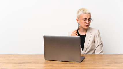Teenager girl with short hair with a laptop with tired and sick expression