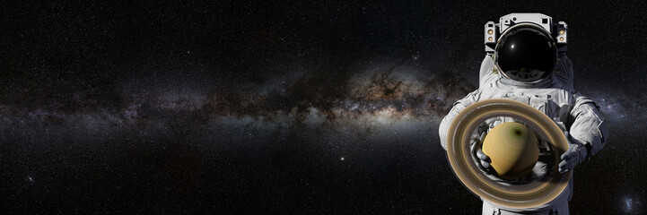 astronaut holding planet Saturn, moons orbiting the gas giant © dottedyeti