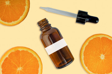Vitamin C serum in cosmetic bottle with dropper, sliced orange on white background. Health care concept