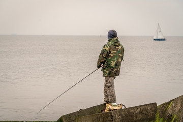 Naklejka premium Man fishing from the pier