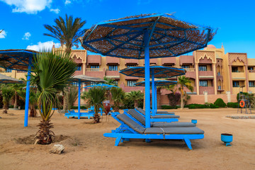 Sun umbrellas and chaise lounges on tropical beach. Concept of rest, relaxation, holidays, resort