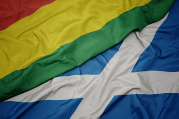 waving colorful flag of scotland and national flag of bolivia.