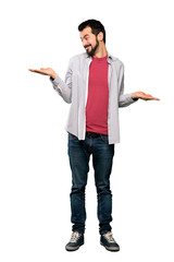 Full-length shot of Handsome man with beard holding copyspace with two hands over isolated white background