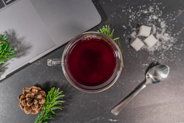 Top down cup of red tea with laptop, sugar and autumn decorations