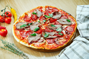 Italian, homemade pizza with meat, salami and hot pepper on a wooden table. Top view food with copy space. Flat lay