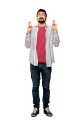 Full-length shot of Handsome man with beard with fingers crossing and wishing the best over isolated white background