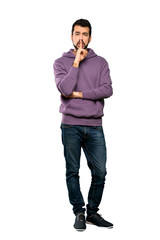 Fototapeta premium Full-length shot of Handsome man with sweatshirt showing a sign of silence gesture putting finger in mouth over isolated white background