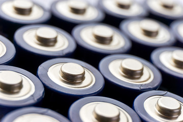 Batteries in rows. Close-up or macro of the positive poles of blue alkaline AA batteries. Image with selective focus.