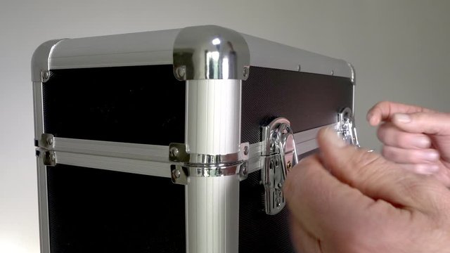 Close POV slow motion shot of a man&rsquo;s hands securing the latches on the lid of a protective storage case / flight case. 