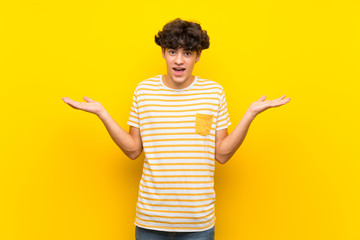 Young man over isolated yellow wall with shocked facial expression