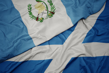 waving colorful flag of scotland and national flag of guatemala.