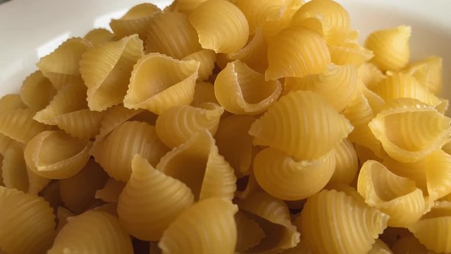 Conchiglie rigate close-up. Pasta falling into a white plate. 3840*2160 4K UHD Stock footage
