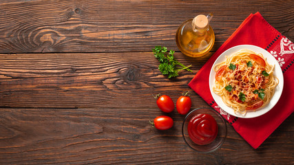 Pasta carbonara with tomato sauce and minced meat, grated parmesan cheese and fresh parsley - homemade healthy italian pasta on rustic wooden background. Flat lay. Top view.