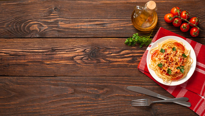 Obraz na płótnie Canvas Pasta carbonara with tomato sauce and minced meat, grated parmesan cheese and fresh parsley - homemade healthy italian pasta on rustic wooden background. Flat lay. Top view.