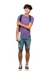 A full-length shot of a Young student man looking up while smiling over isolated white background