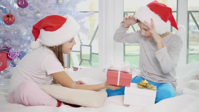 Siblings comparing their presents. The boy is happy with a big gift box while his sister have a small one.