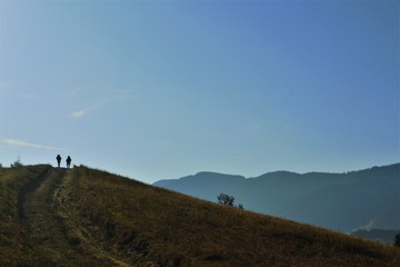 Obraz na płótnie Canvas two tourists in the mountains on the horizon
