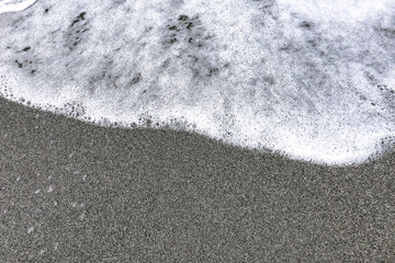 Obraz premium A soft foamy wave gradually covering pure sea sand. With space for text.