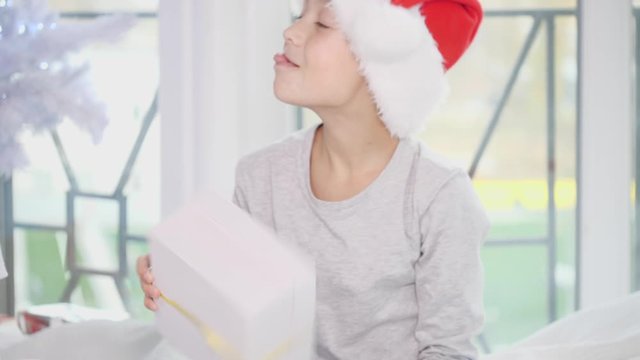Boy is happy with a big gift box, and he is sitting on the bed, gloating and laughing at his sister.