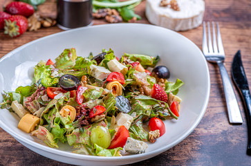 Gourmet green salad with cheese, grape, strawberries and cherry